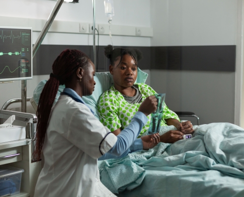 An African practitioner doctor standing beside a sick young patient during uterine fibroid embolisation failure