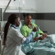 An African practitioner doctor standing beside a sick young patient during uterine fibroid embolisation failure