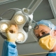 A woman in a surgical gown is operating a light fixture during a hysterectomy