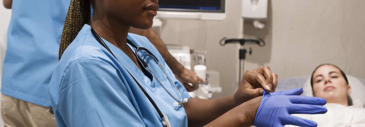 A uterine fibroid embolisation specialist in South Africa sitting with a patient and putting on gloves
