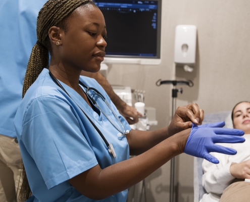 A uterine fibroid embolisation specialist in South Africa sitting with a patient and putting on gloves