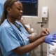 A uterine fibroid embolisation specialist in South Africa sitting with a patient and putting on gloves
