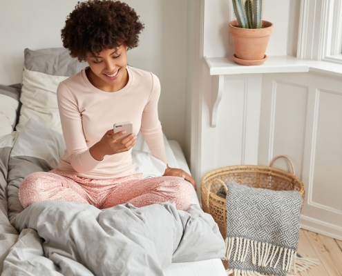 A lady sitting on a bed and enjoying recreation time after uterine fibroid embolisation