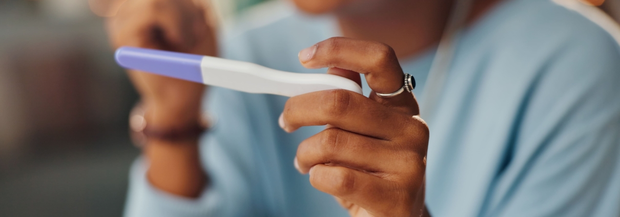 A close-up of a young woman looking at a pregnancy test to show the impact of UFE and future pregnancies.