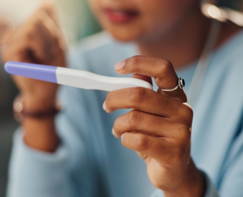 A close-up of a young woman looking at a pregnancy test to show the impact of UFE and future pregnancies.