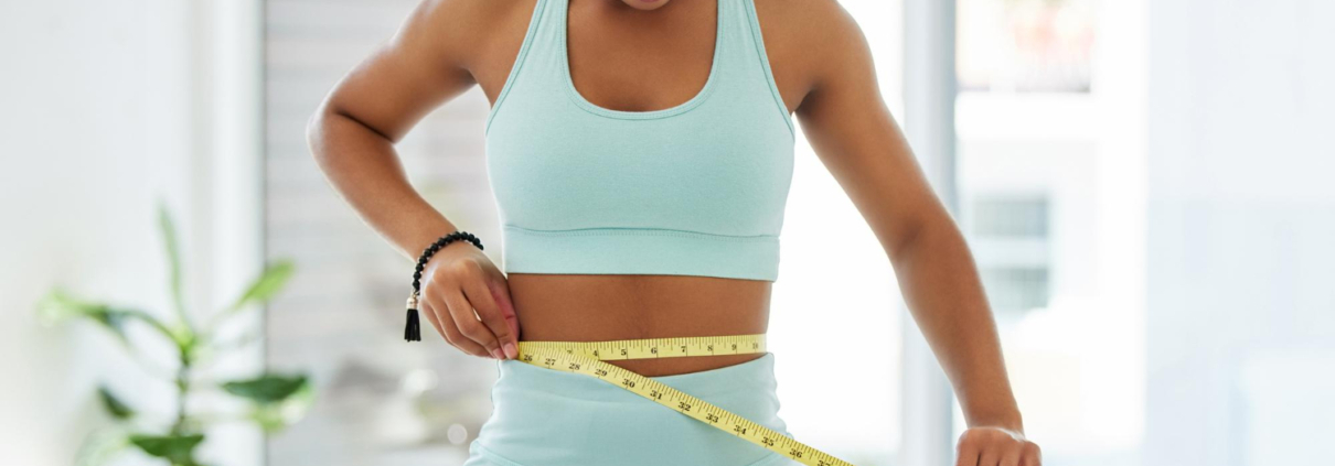 A young lady using measuring tape across her waste to gauge how UFE and weight affect each other