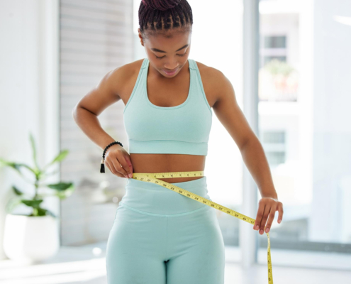 A young lady using measuring tape across her waste to gauge how UFE and weight affect each other