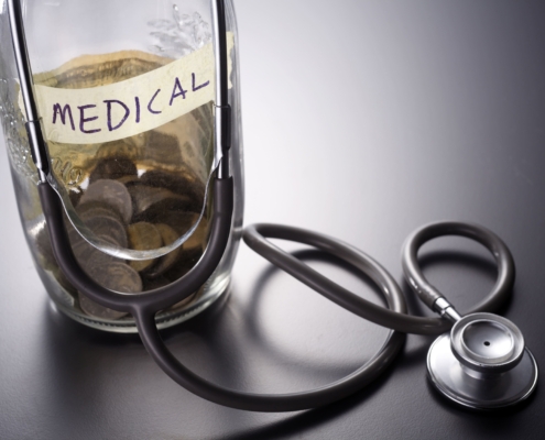 Coins in a medical savings jar next to a stethoscope for UFE fibroids cost.