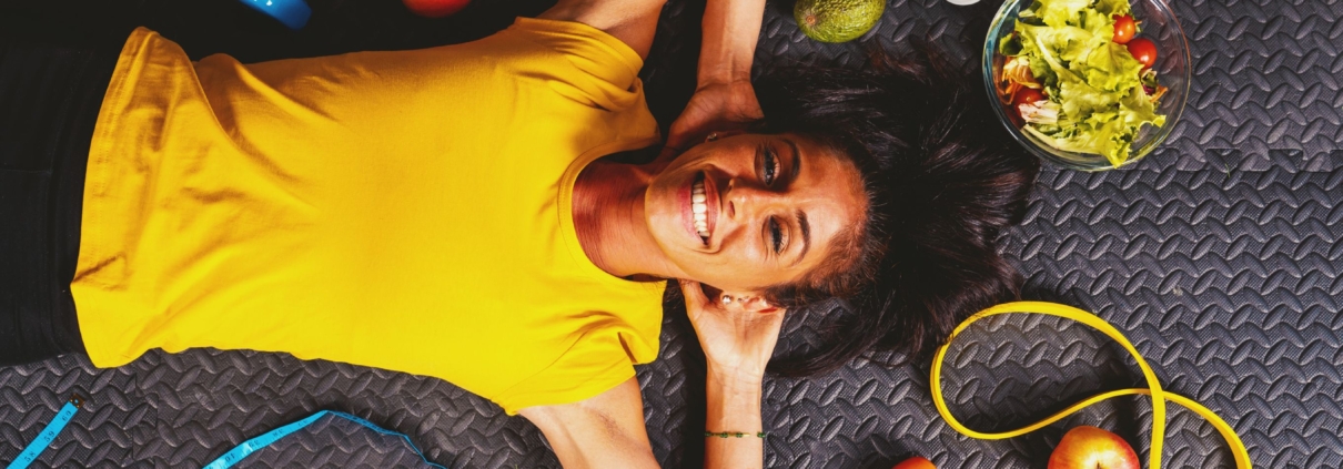 A healthy, smiling young woman lying on the floor while managing fibroids after UFE