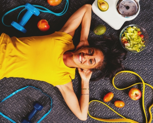 A healthy, smiling young woman lying on the floor while managing fibroids after UFE