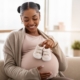 A smiling pregnant lady holding baby shoes against her tummy for postpartum bleeding embolisation